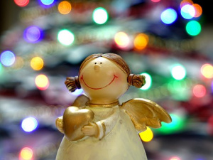 Hymyilevä enkeli värikkäiden jouluvalojen edesssä.